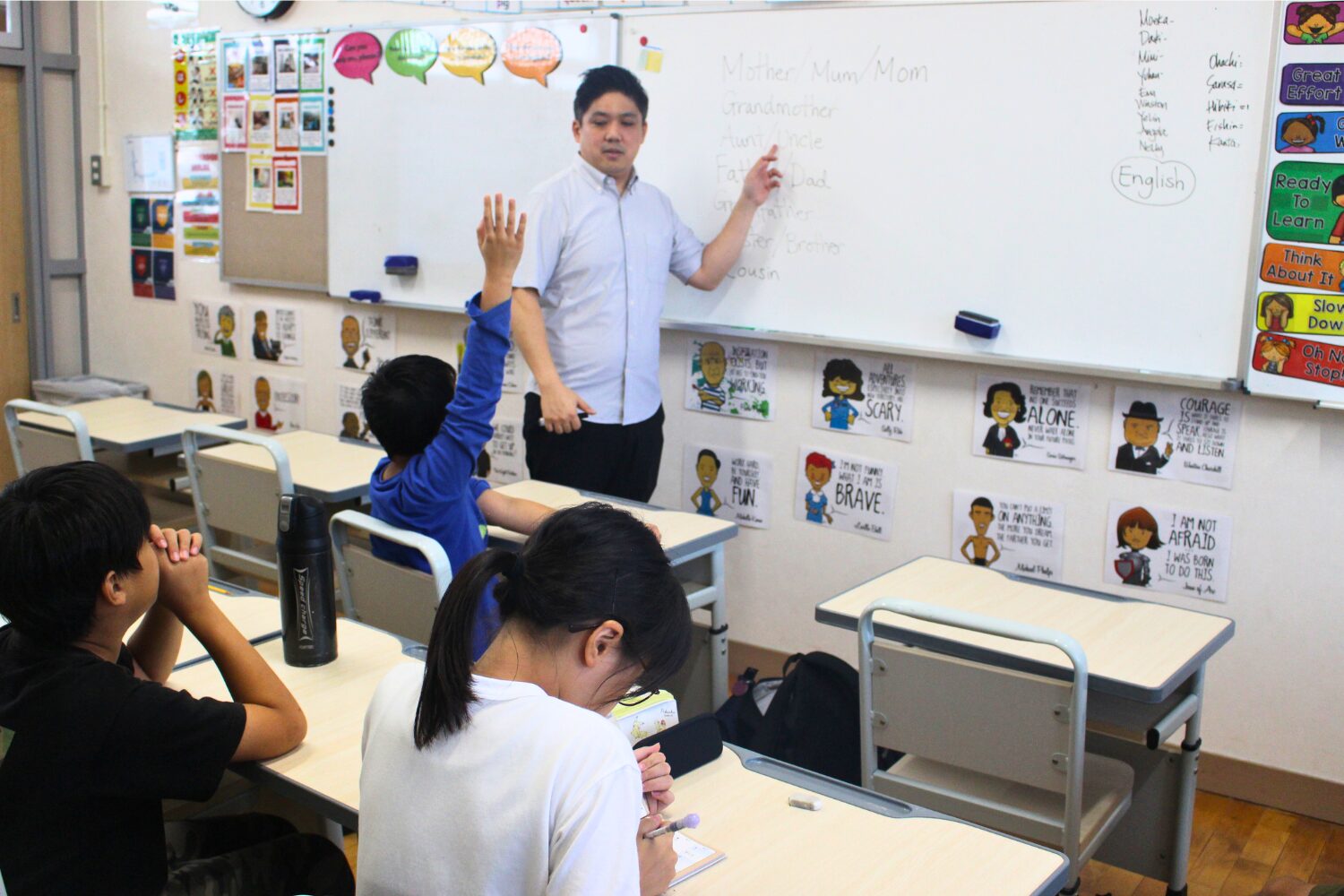 Intensive English After-school Club at One World International School - Teacher pointing at the board, and kid with hand up